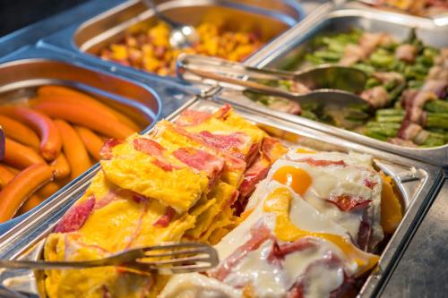 a buffet filled with trays of food with forks at Hotel International in Tatranská Lomnica