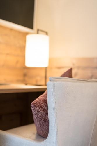 a chair in front of a desk with a lamp at Alpenhotel Tirolerhof in Fulpmes