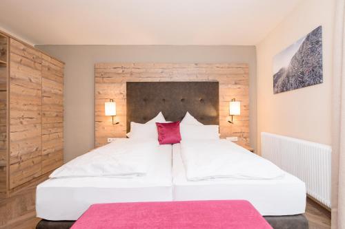 a bedroom with two white beds with red pillows at Alpenhotel Tirolerhof in Fulpmes