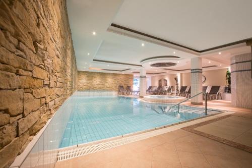 a swimming pool in a building with a stone wall at Alpenhotel Tirolerhof in Fulpmes