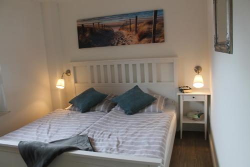a bedroom with a white bed with blue pillows at Küstenzauber in Schönhagen