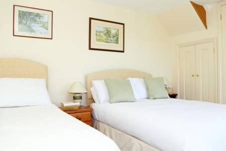 a bedroom with two beds and two pictures on the wall at Dove Lodge in Painswick