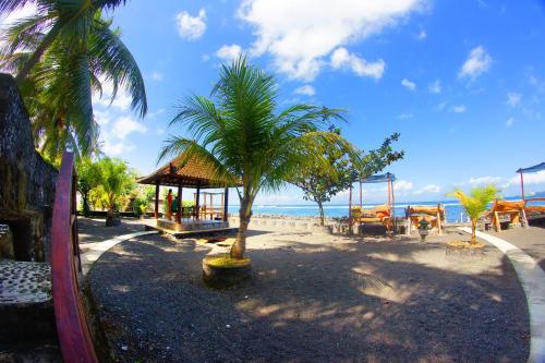 a palm tree on a beach with a playground at Crystal Beach Bali in Candidasa