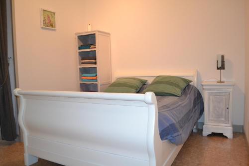 a white bed with green pillows in a bedroom at Gites Rural De La Douix in Châtillon-sur-Seine