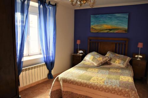 um quarto com uma cama com paredes azuis e uma janela em Casa Rural El Camino em Montemayor de Pililla