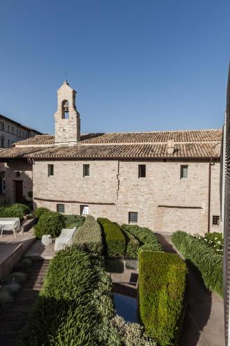 a large stone building with bushes and a tower at Nun Assisi Relais & Spa Museum in Assisi