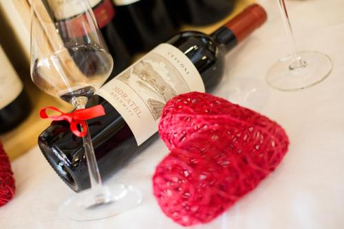 a red knitted heart next to a bottle of wine at Olympic SPA Hotel - Adults Only in Vigo di Fassa