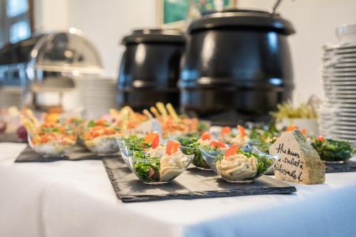 a table with a bunch of salads in small cups at Cetatuia in Măgura