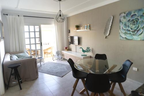 uma sala de estar com uma mesa de vidro e cadeiras em Casa del Mar em Playa de San Juan