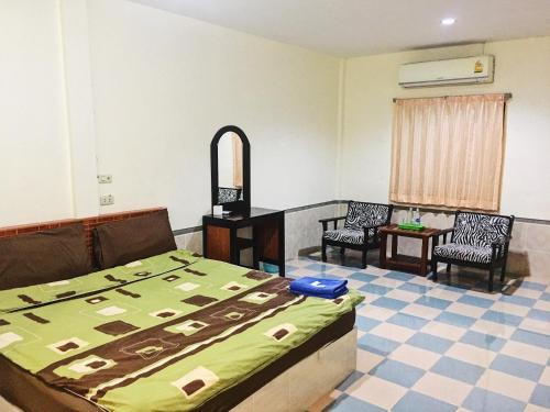 a bedroom with a bed and two chairs and a table at Purinplace in Pluak Daeng