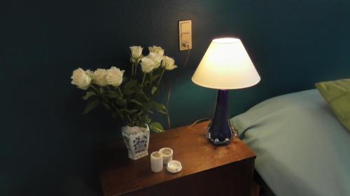 a lamp on a table next to a bed with flowers at Djurs-BnB - Rimsøhuset in Rimsø