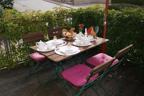 a wooden table with chairs and a tea set at Gästehaus 'Alte Bäckerei' Kaffeehaus in Großbundenbach