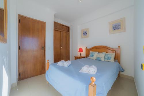 Un dormitorio con una cama azul con toallas. en Atlantida by Garvetur, en Quarteira