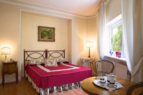 ローマにあるスイート オリアーニのベッドルーム(赤いベッド1台、テーブル付)