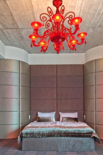 a bedroom with a large bed with a red chandelier at G Design Hotel in Ljubljana