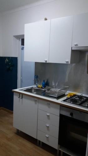 a kitchen with white cabinets and a sink and a stove at Casa da Madrinha II in Monte Gordo