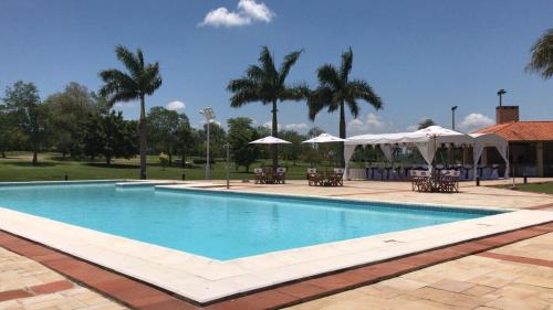 a swimming pool with tables and umbrellas in a park at Carlos Franco Country Golf in Arroyos y Esteros