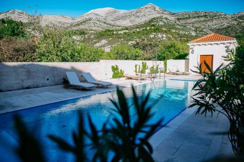 une piscine avec des chaises et des montagnes en arrière-plan dans l'établissement Apartments Villa Riva, à Slano