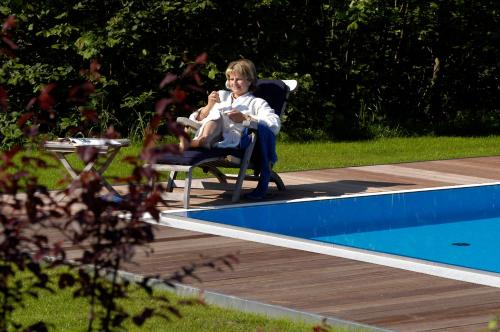 a woman sitting in a chair next to a swimming pool at Weingut Tauss in Leutschach