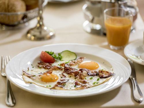a plate of eggs on a table with a glass of orange juice at Appartement Hotel Seerose in Immenstaad am Bodensee