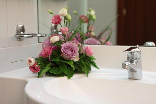 a bouquet of pink roses sitting on a bathroom sink at Euro Hotel in Cascina