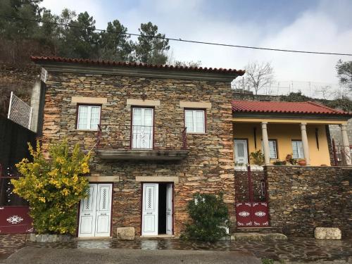 uma casa de pedra com portas brancas e uma parede de tijolos em Casa da Escola Antiga em Manteigas