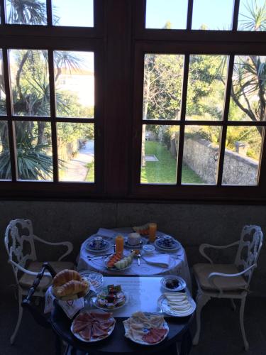 a table with plates of food in a room with windows at Casa Manuel Espregueira e Oliveira in Viana do Castelo