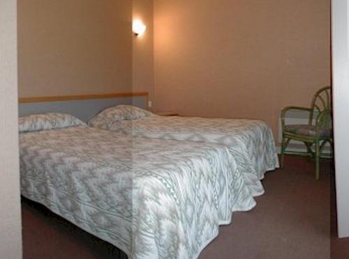 a hotel room with a bed and a chair at Hôtel du Bout du Monde in Saint-Flour
