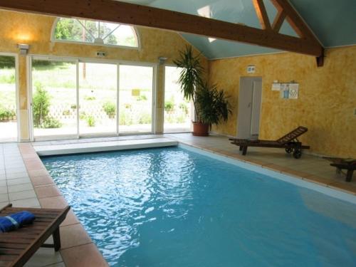 a large swimming pool in a house with a large window at Hôtel du Bout du Monde in Saint-Flour