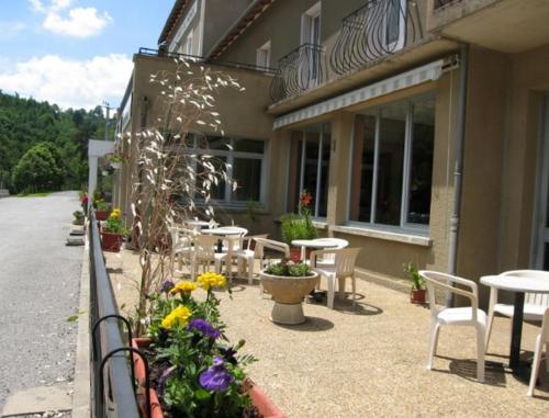 a patio with tables and chairs next to a building at Hôtel du Bout du Monde in Saint-Flour
