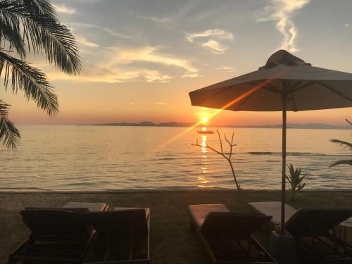 a sunset over the water with chairs and an umbrella at Koh Kwang Seaview in Klong Muang Beach