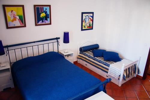 ein Schlafzimmer mit einem Bett mit blauen Laken und Bildern an der Wand in der Unterkunft Milfontes Villa in Vila Nova de Milfontes