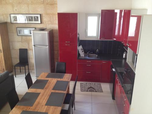 Bourg-sur-GirondeにあるMaison de Ville 8 personnesのキッチン(赤いキャビネット、木製テーブル付)