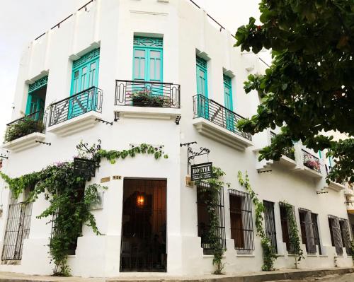 a white building with blue windows and a door at Casa La Bella Samaria Boutique in Santa Marta