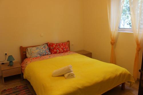 een slaapkamer met een geel bed en handdoeken bij Aaron Apartments in Ferma