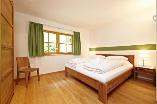 ein Schlafzimmer mit einem Bett, einem Stuhl und einem Fenster in der Unterkunft Ferienwohnungen Zugspitze in Grainau