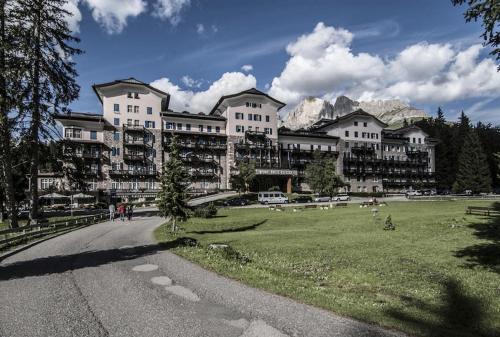 a large building with a grass field in front of it at Residence Grand Hotel Carezza in Nova Levante