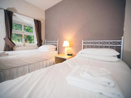 two beds in a room with a window at The Lantern Pike Inn in Hayfield