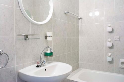 a bathroom with a sink and a mirror and a tub at Pafia 3 Holiday Apartment in Paphos City