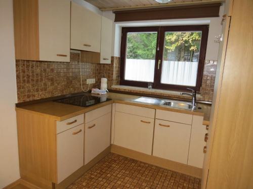 阿尔戈伊地区伊斯尼Ferienhaus Ziegler的厨房配有白色橱柜、水槽和窗户