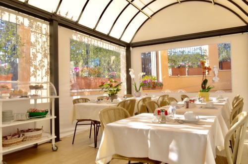 a restaurant with white tables and chairs and windows at Sourire Hotel in Rome