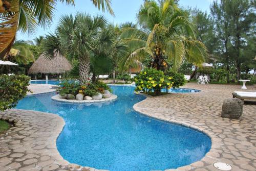 a swimming pool with palm trees and a resort at Hotel Istirinchá in Nautla