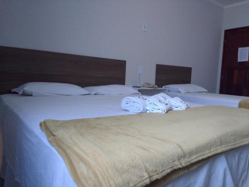 two beds in a hotel room with towels on them at Pousada da Pedra in Delmiro Gouveia