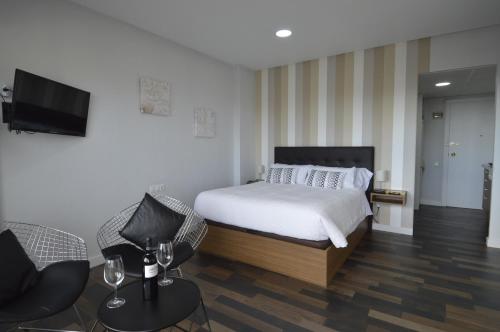 a bedroom with a bed and a flat screen tv at Lukentum Suites in Alicante