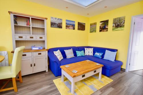 a living room with a blue couch and a table at Creek View in Wootton Bridge