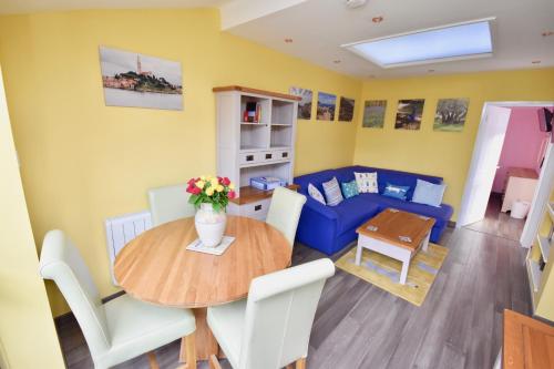 a living room with a table and a blue couch at Creek View in Wootton Bridge