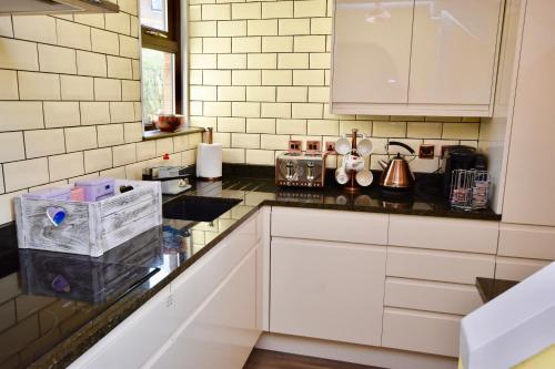a kitchen with white cabinets and black counter tops at Creek View in Wootton Bridge