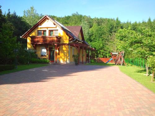 a brick driveway in front of a house with a playground at Nefelejcs Fagyizó és Apartmanház in Kistolmács
