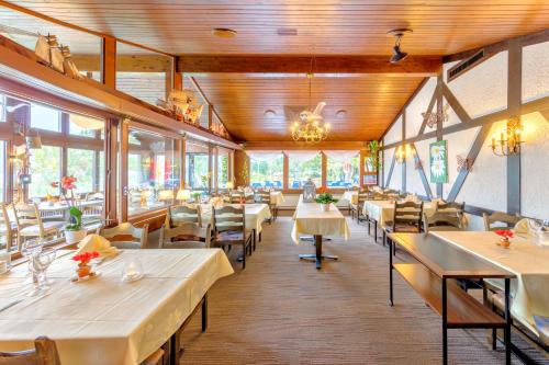 a restaurant with white tables and chairs and windows at Hotel Restaurant Möve in Faulensee