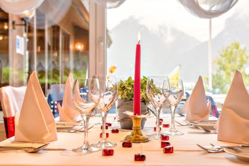 a table with wine glasses and a candle on it at Hotel Restaurant Möve in Faulensee